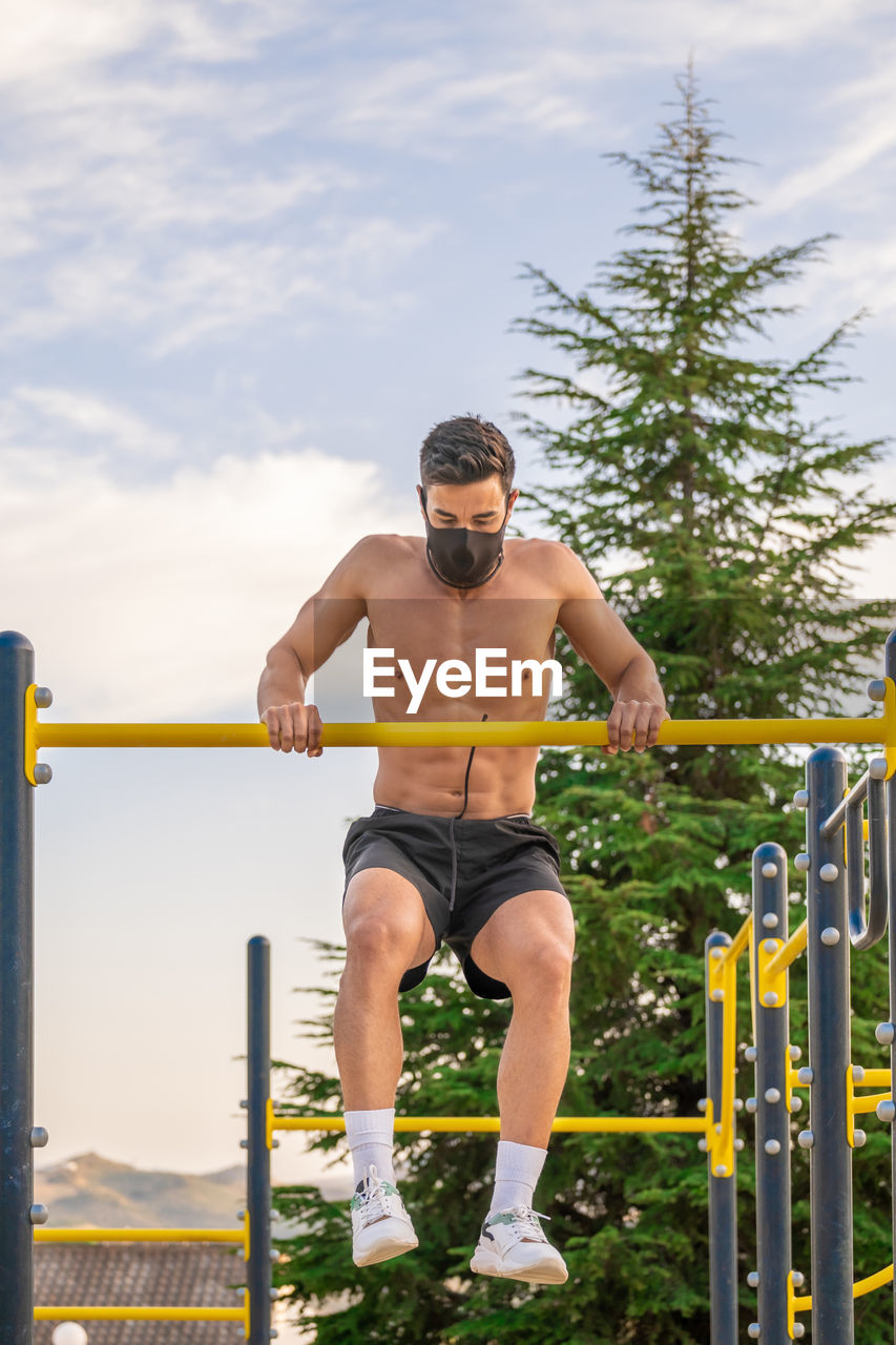 Young man wearing mask exercising at playground