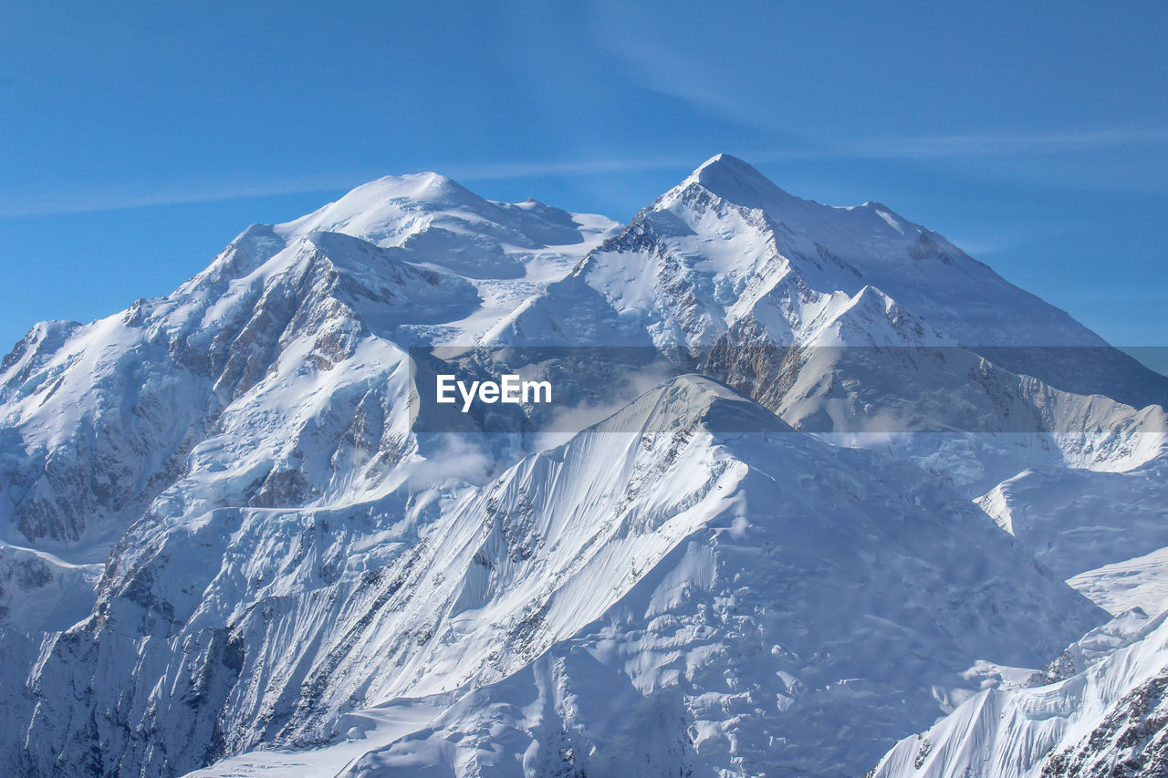 Scenic view of snowcapped mountains against blue sky