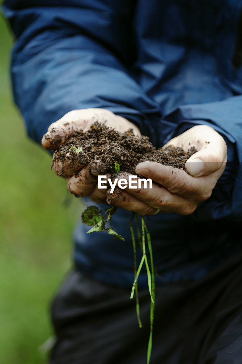 Midsection of man holding soil while standing at farm