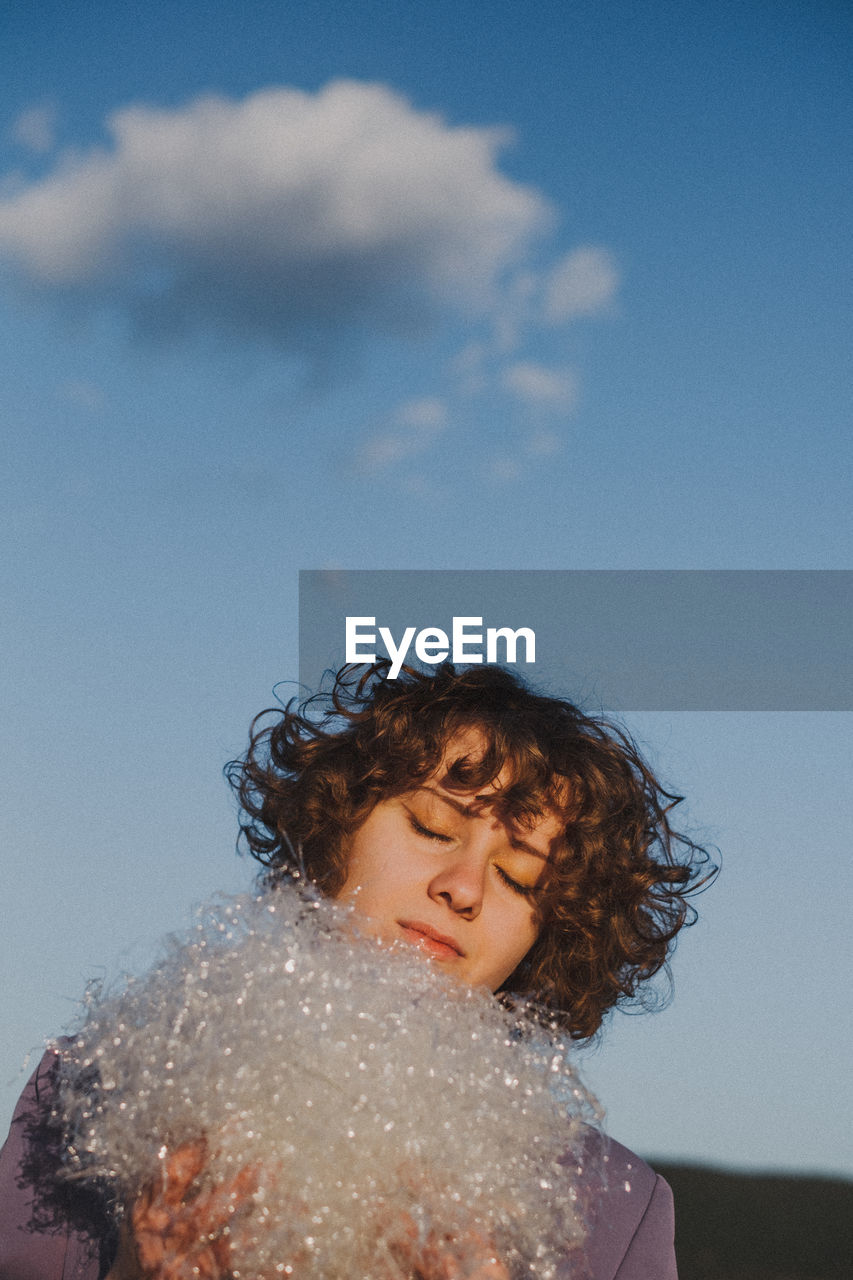 Woman with at plastic against blue sky