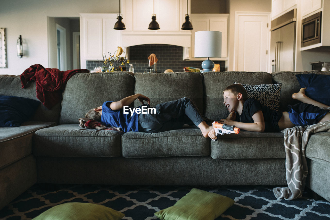 Happy brothers lying on sofa at home