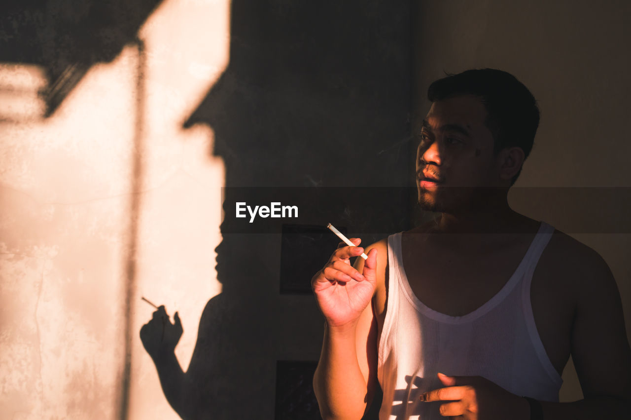 Young man holding cigarette at home