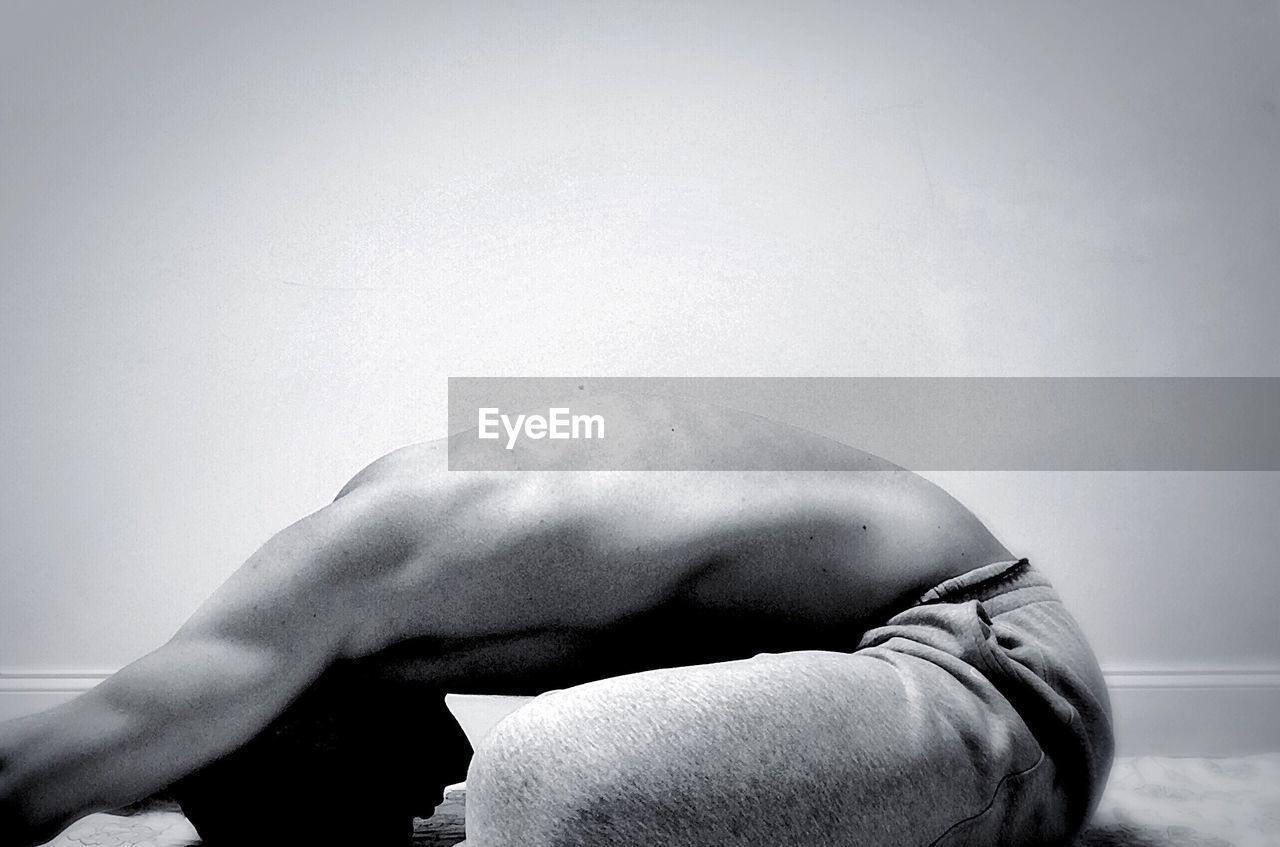 Side view of man bending on floor against white background