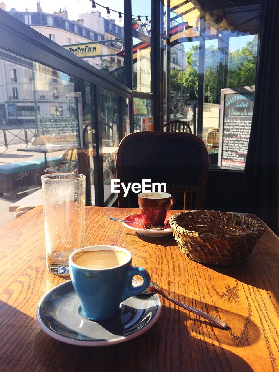 CLOSE-UP OF COFFEE CUP ON TABLE AGAINST CAFE