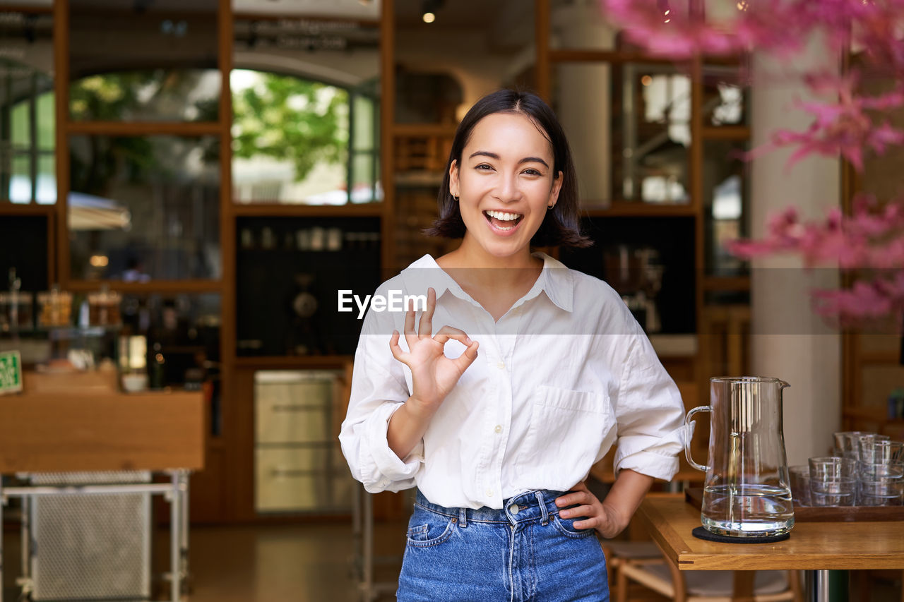 portrait of smiling young woman standing in cafe