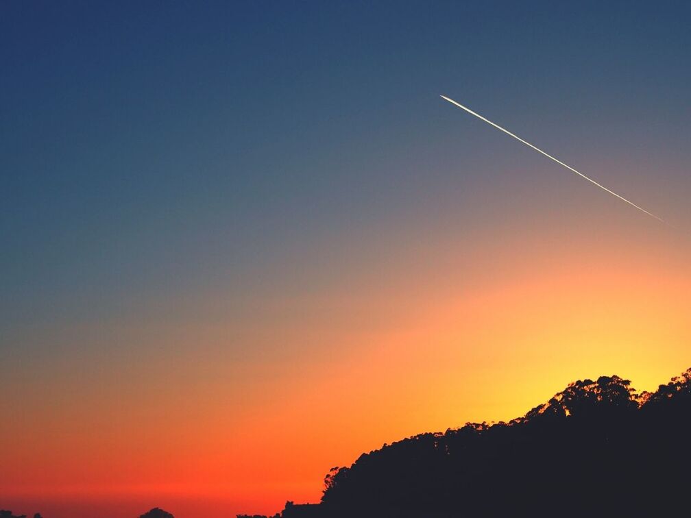 Low angle view of vapor trail in clear sky during sunset