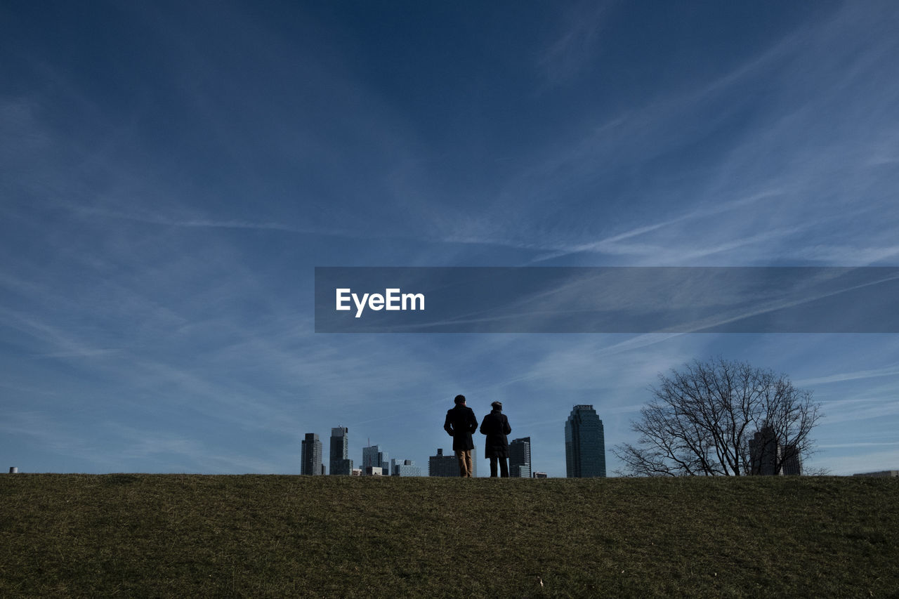 Rear view of man and woman standing on land against sky