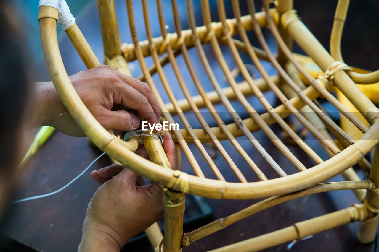 Close-up of man making wicker chair