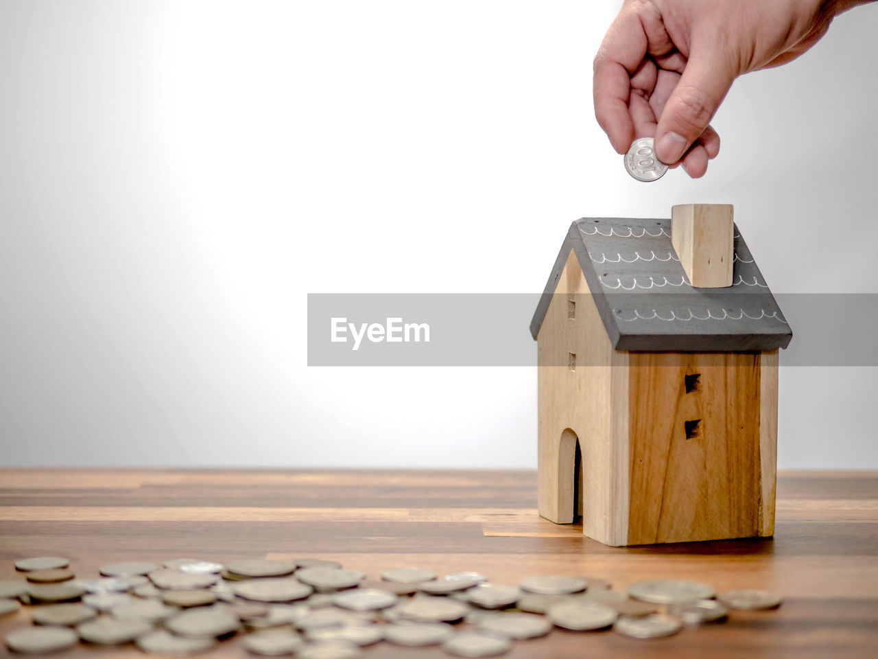 Close-up of hand investing in house on table against white background