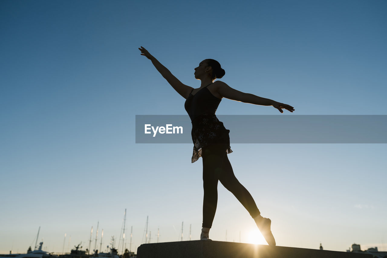 Female ballet dancer practicing during sunset against blue sky