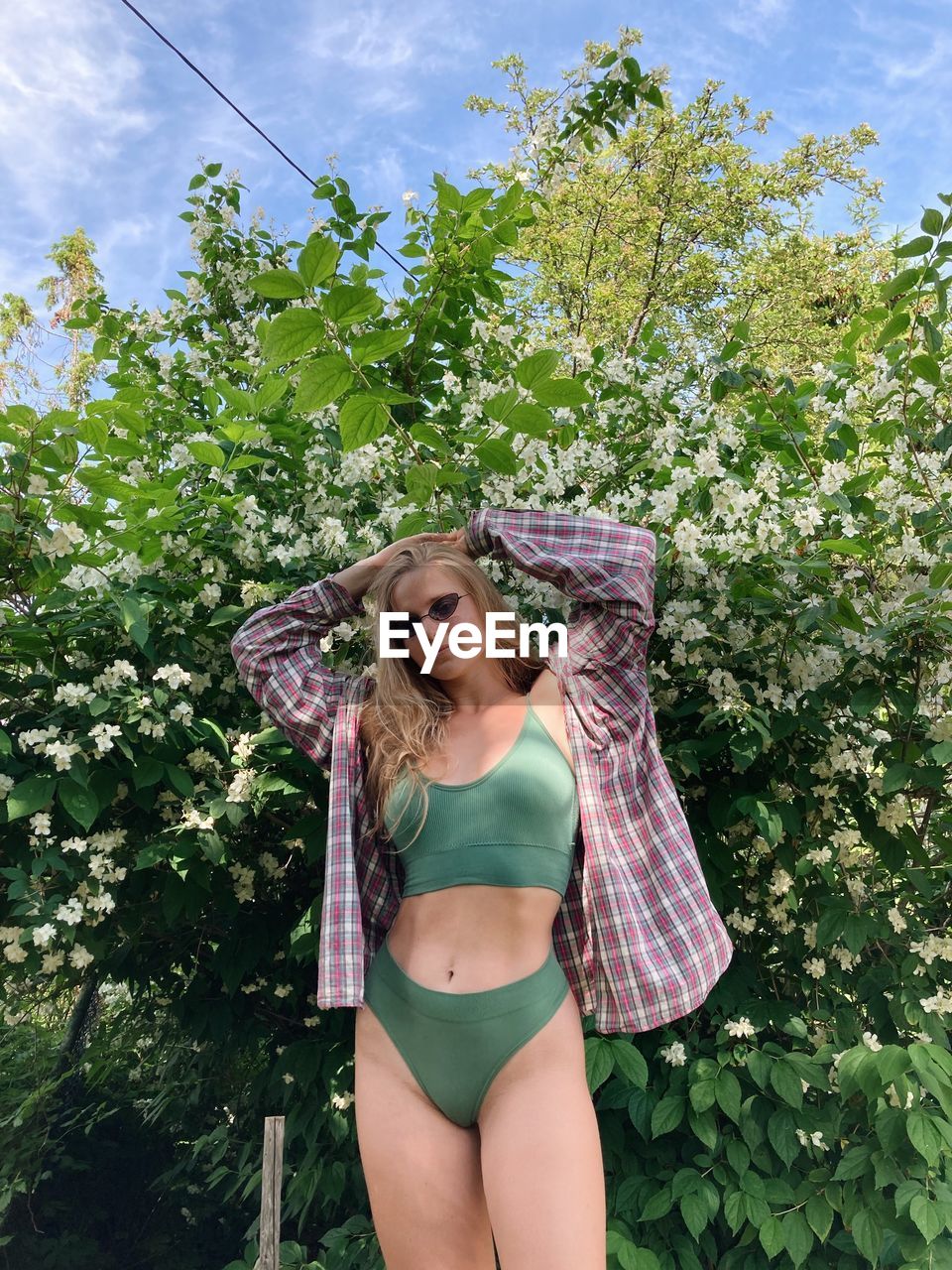 portrait of young woman wearing sunglasses standing against trees