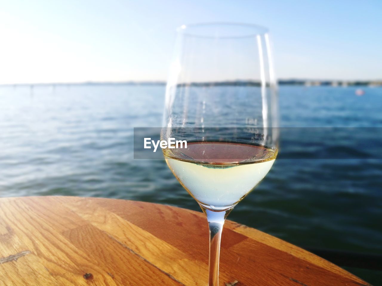 Close-up of wine in front of sea against sky