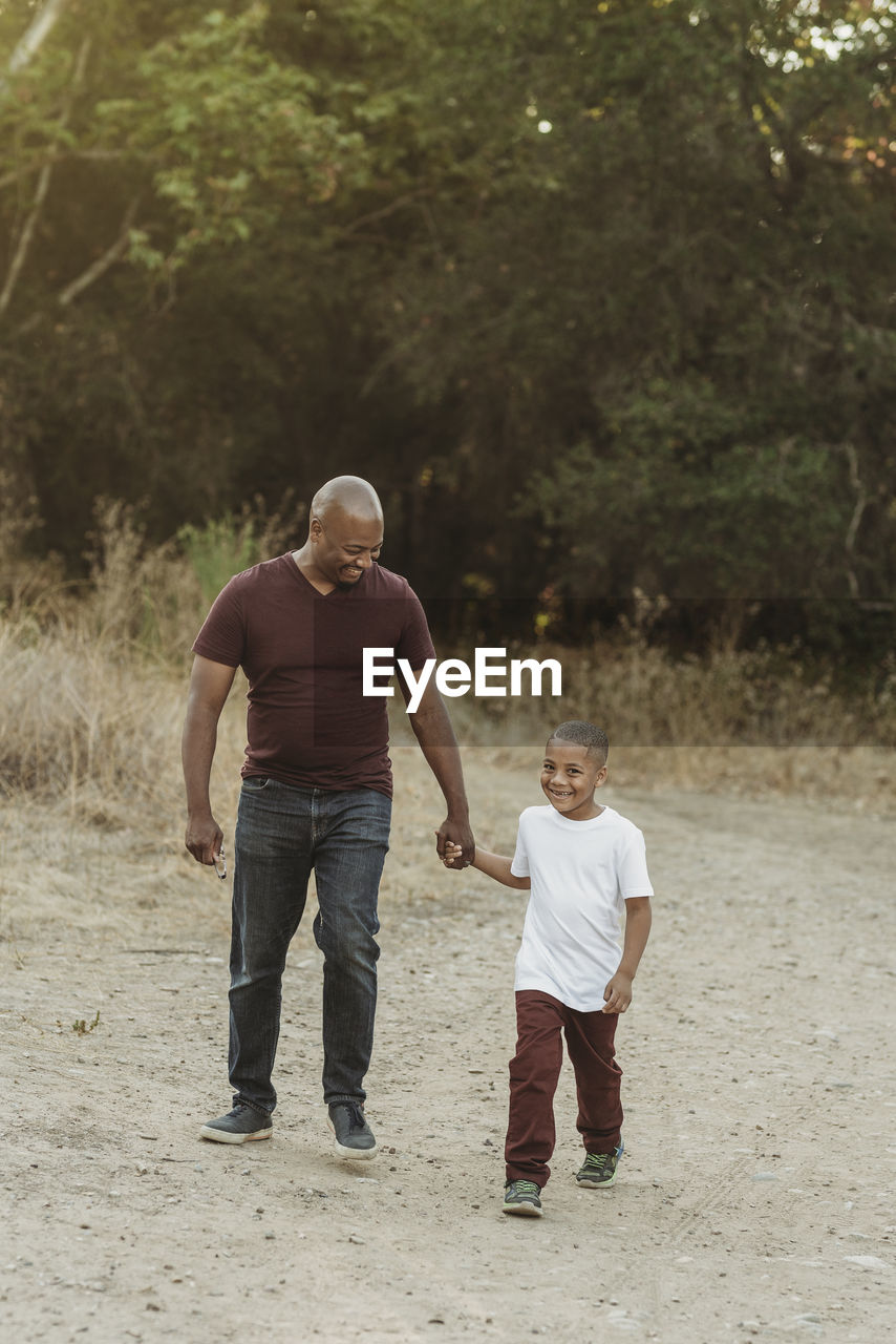 Happy father and son holding hands and walking in field