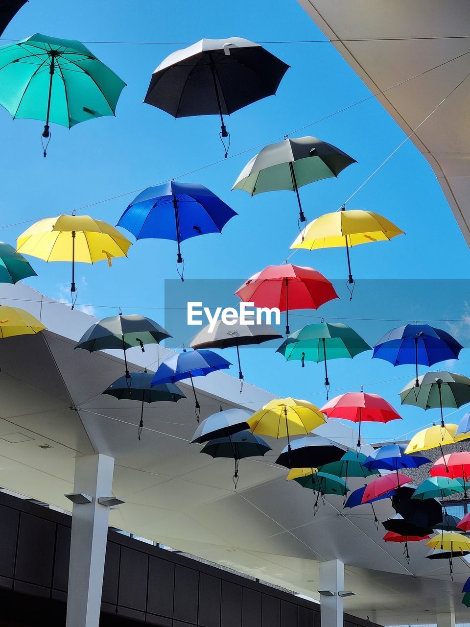 umbrella, protection, security, multi colored, fashion accessory, sky, parasol, low angle view, nature, architecture, no people, large group of objects, day, outdoors, blue, business, in a row, hanging