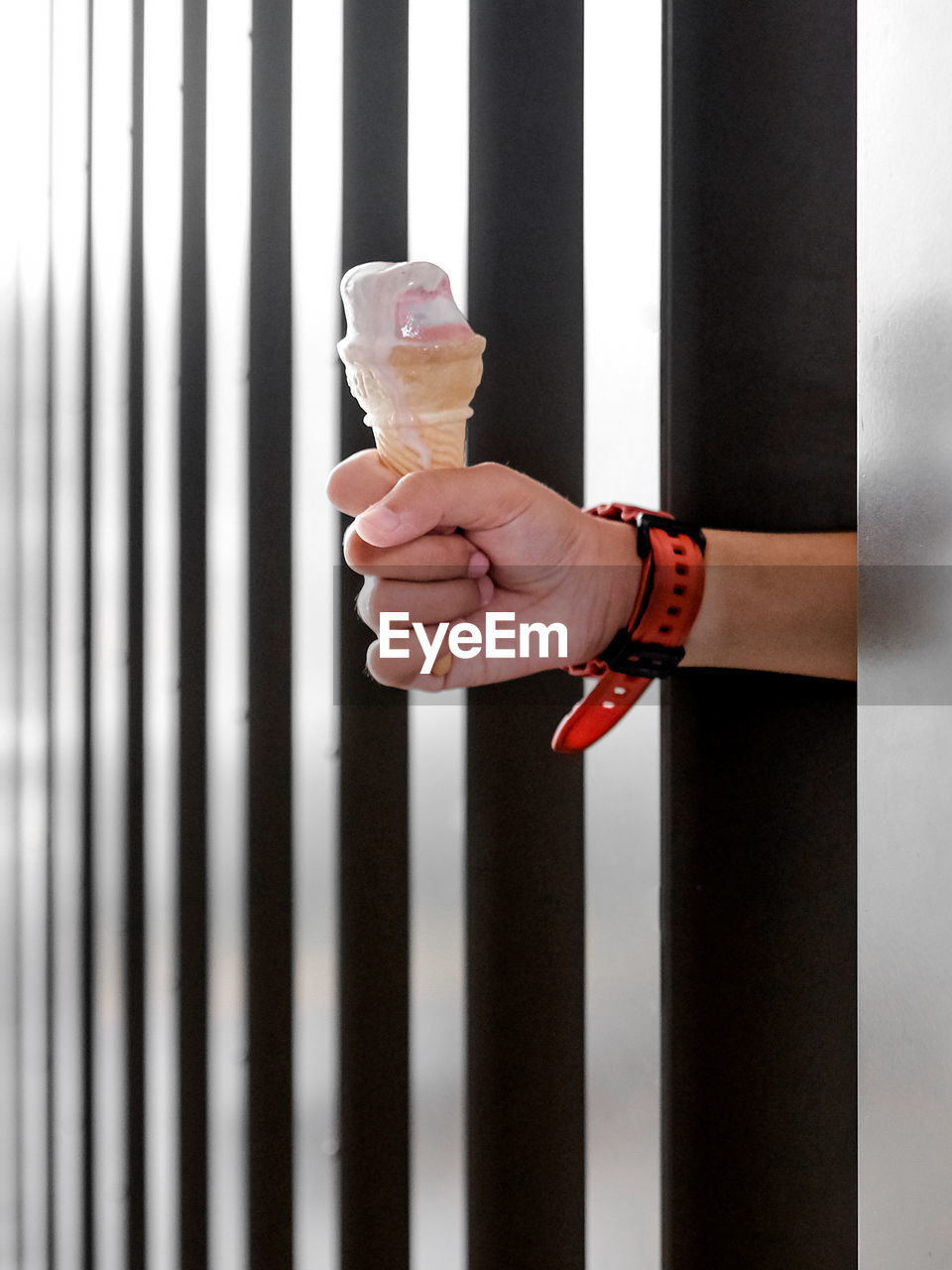 Hand holding ice cream cone between steel post