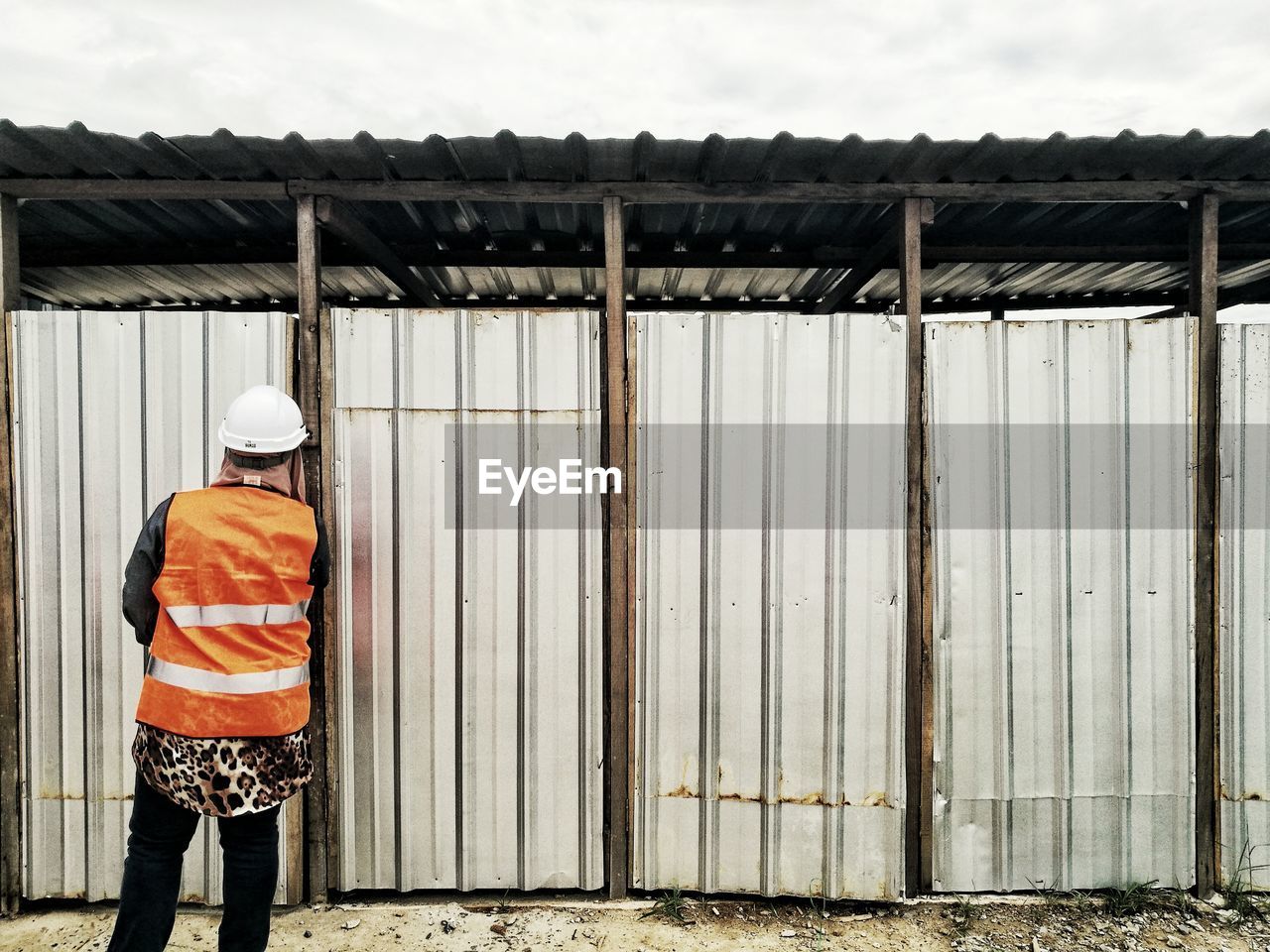 Rear view of worker standing against corrugated iron doors