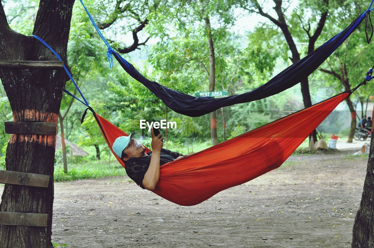 Man using mobile phone while relaxing in hammock