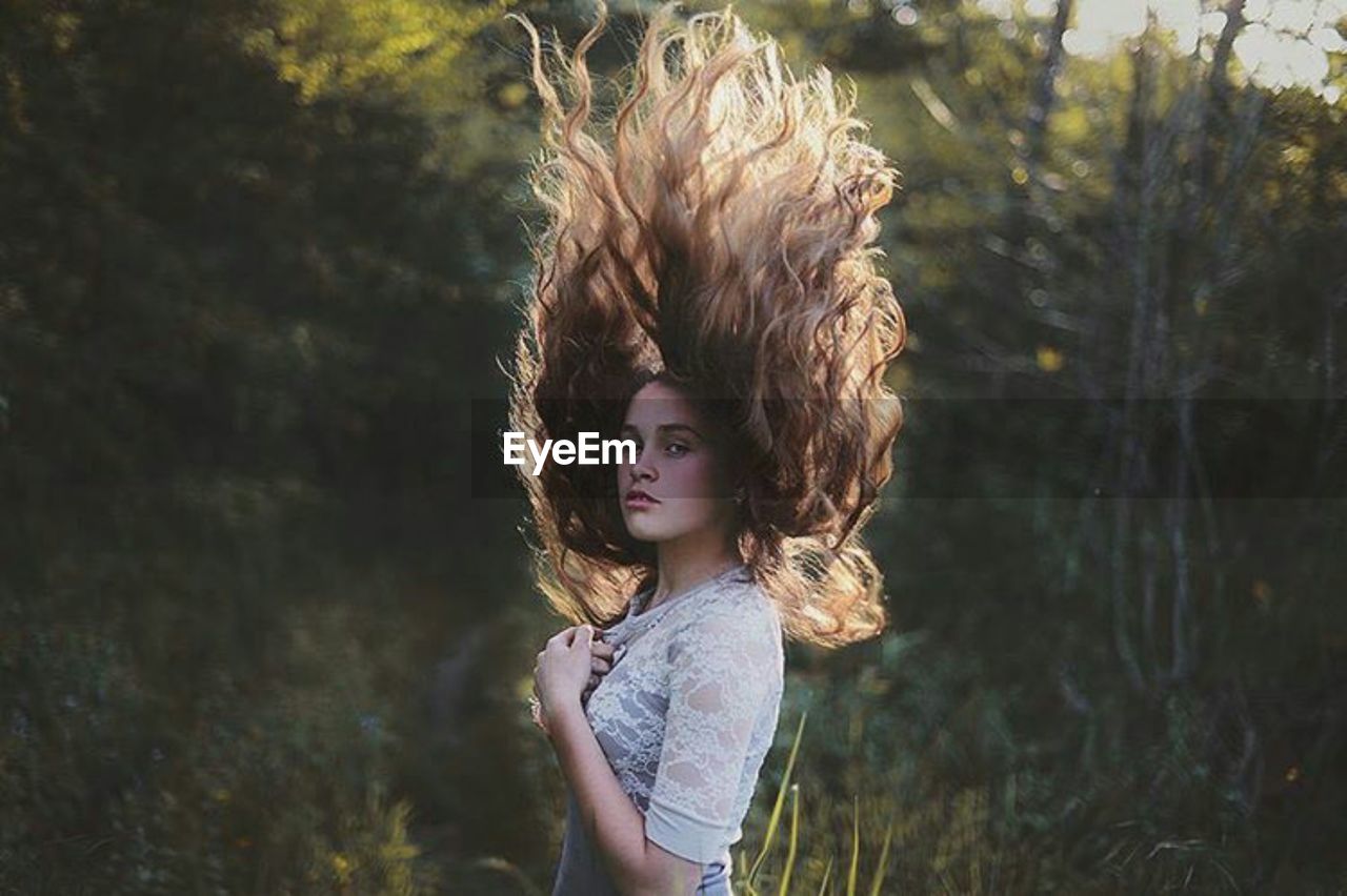 Portrait of woman tossing hair while standing outdoors