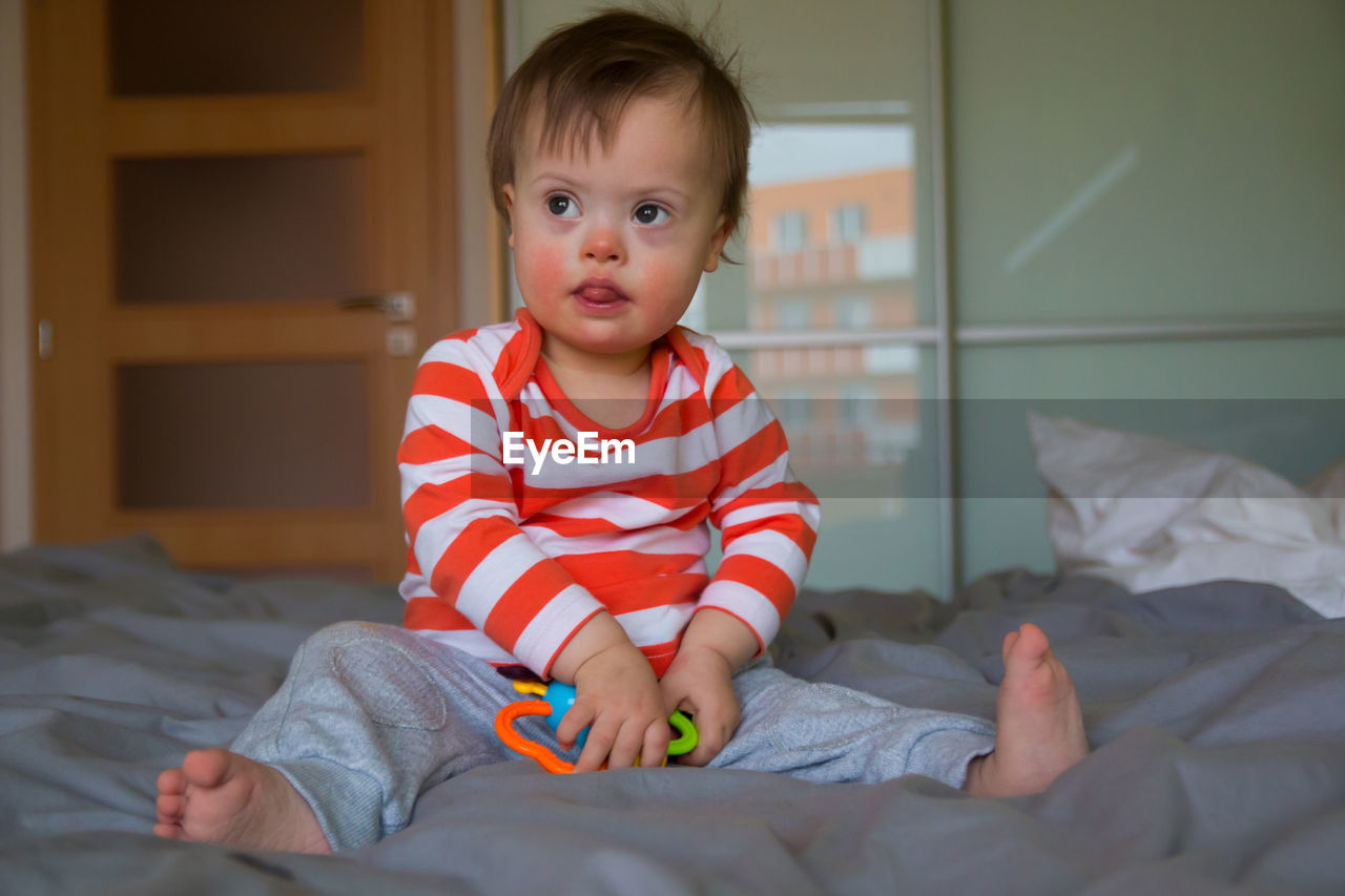 Cute boy with toy sitting on bed