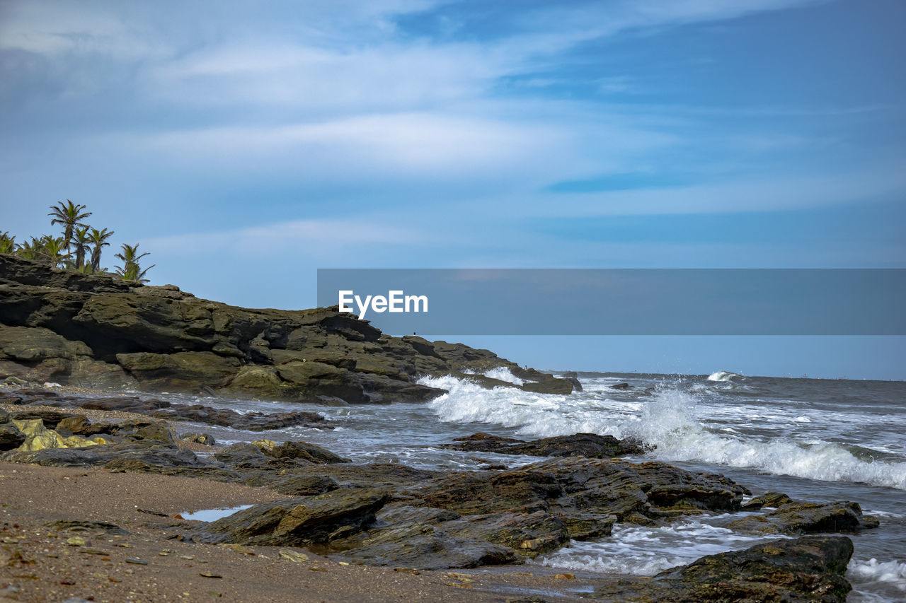 SCENIC VIEW OF ROCKY SHORE AGAINST SKY