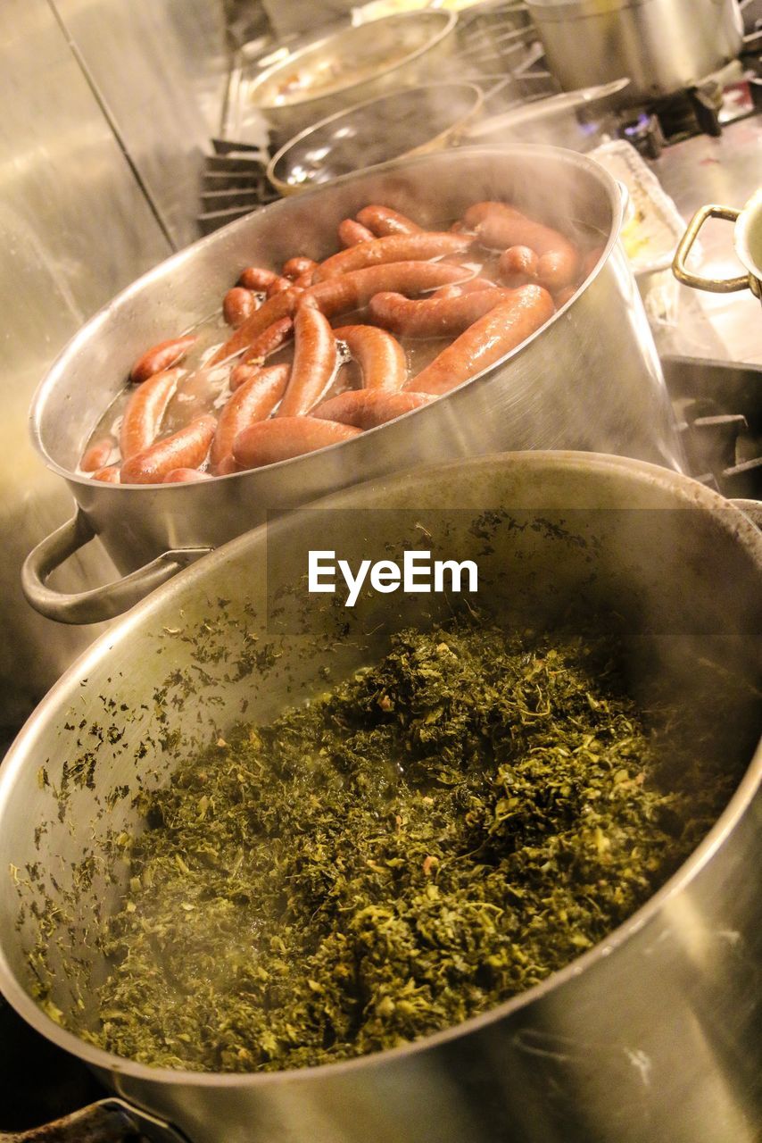 High angle view of kale leaves and sausages cooking in saucepans