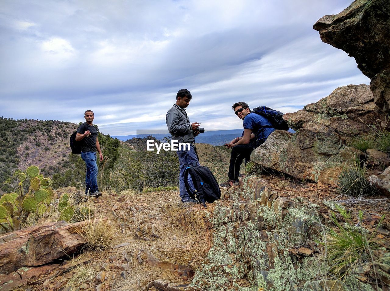 REAR VIEW OF MAN STANDING ON ROCKS