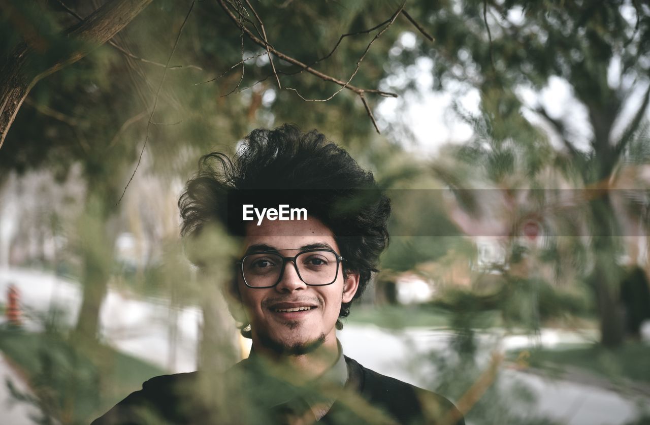 Portrait of smiling young man against trees