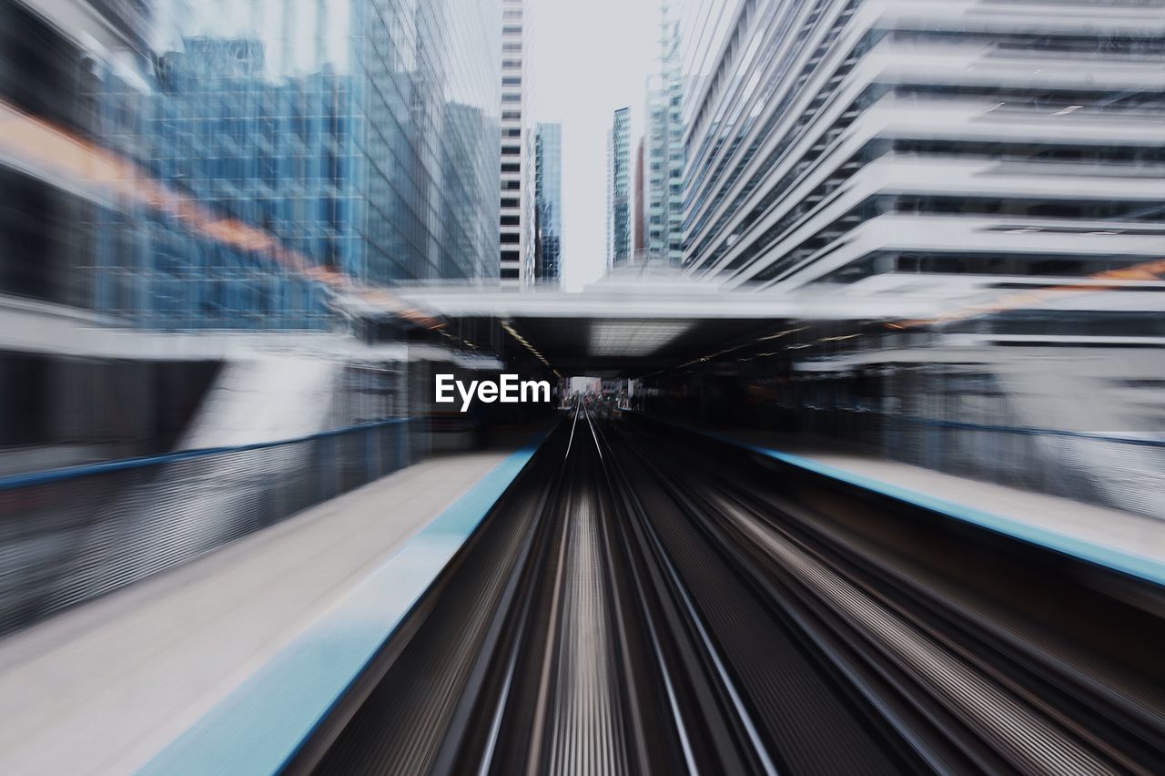 Blurred motion of railroad station amidst buildings in city