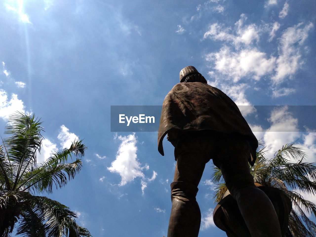 REAR VIEW OF MAN STANDING AGAINST SKY