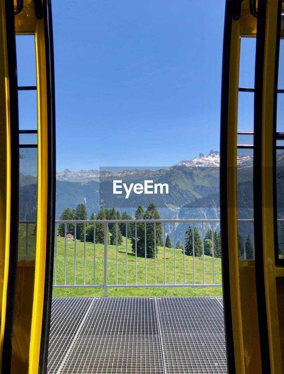 Scenic view of mountains against clear sky seen through window from gondola