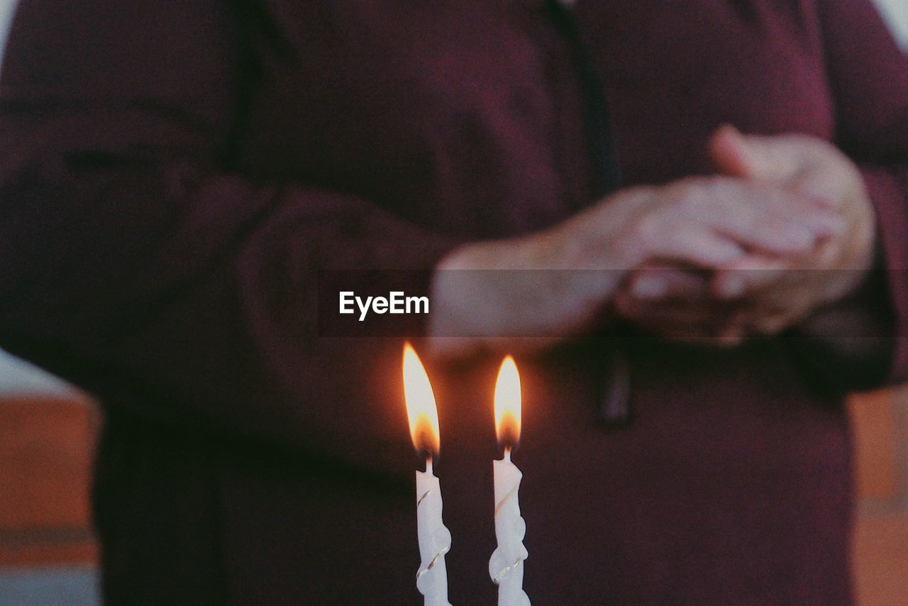 Midsection of person standing by candles