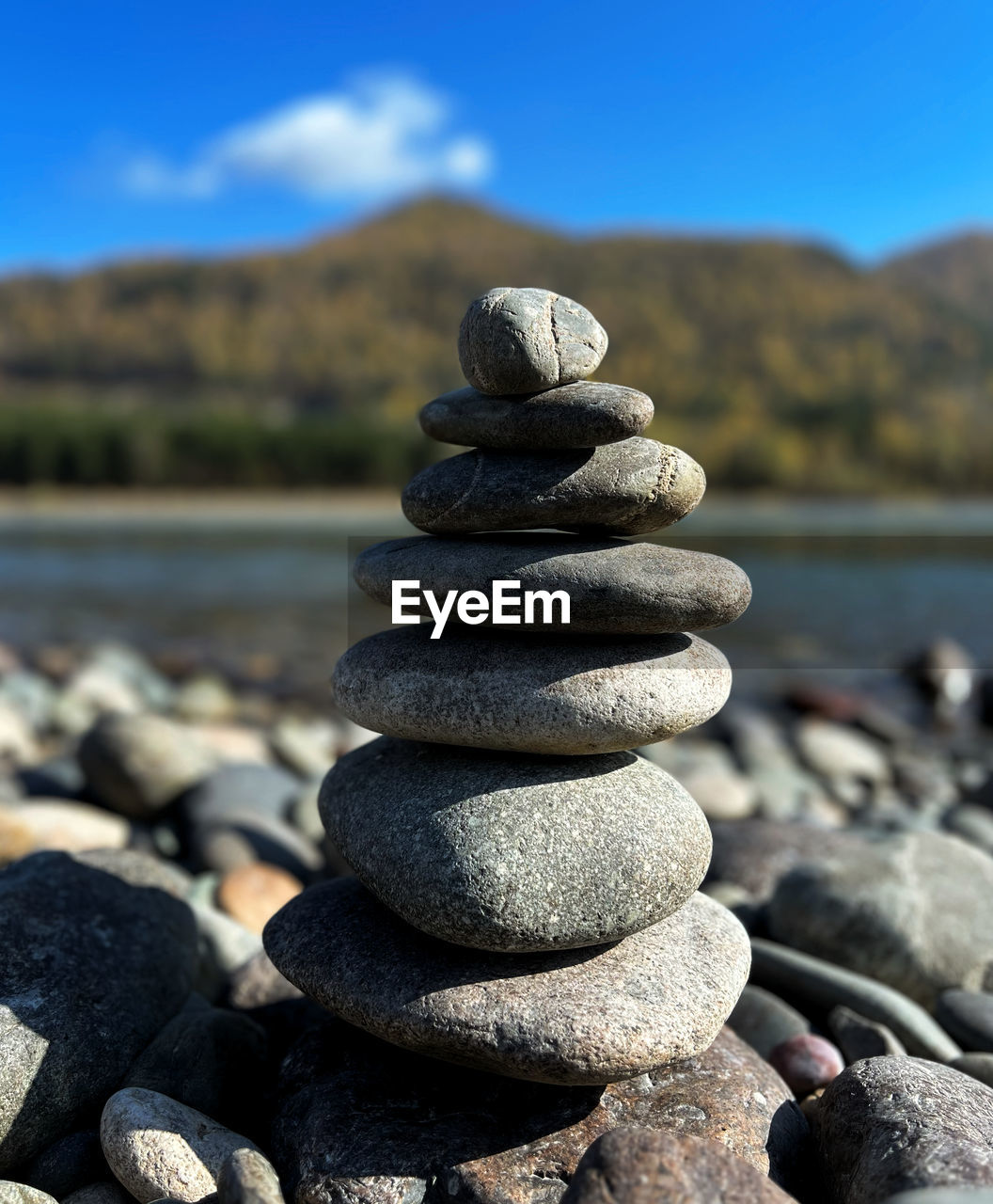balance, rock, pebble, zen-like, stone, nature, shore, sky, tranquility, water, no people, land, focus on foreground, day, tranquil scene, beach, sand, stability, mountain, beauty in nature, sea, outdoors, coast, large group of objects, scenics - nature, sunlight, blue