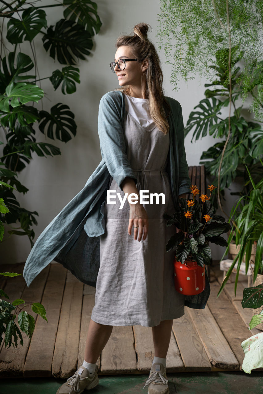 Full length of woman standing against potted plants