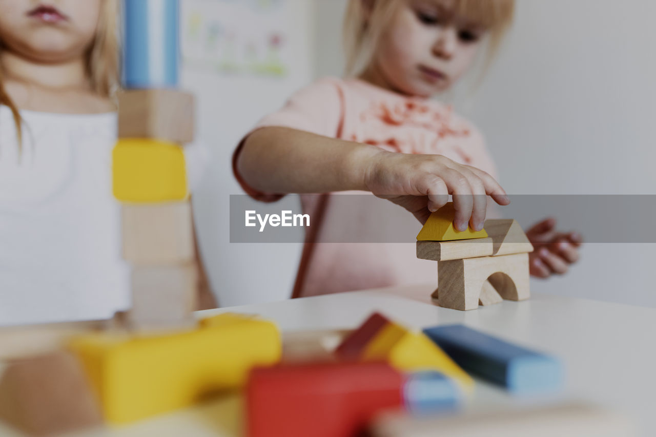 Two child girl sisters playing with colorful wooden toy building blocks. educational children toys