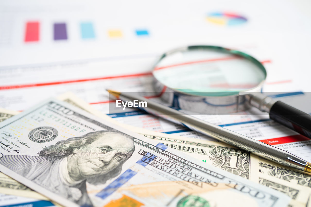 high angle view of magnifying glass on paper currency