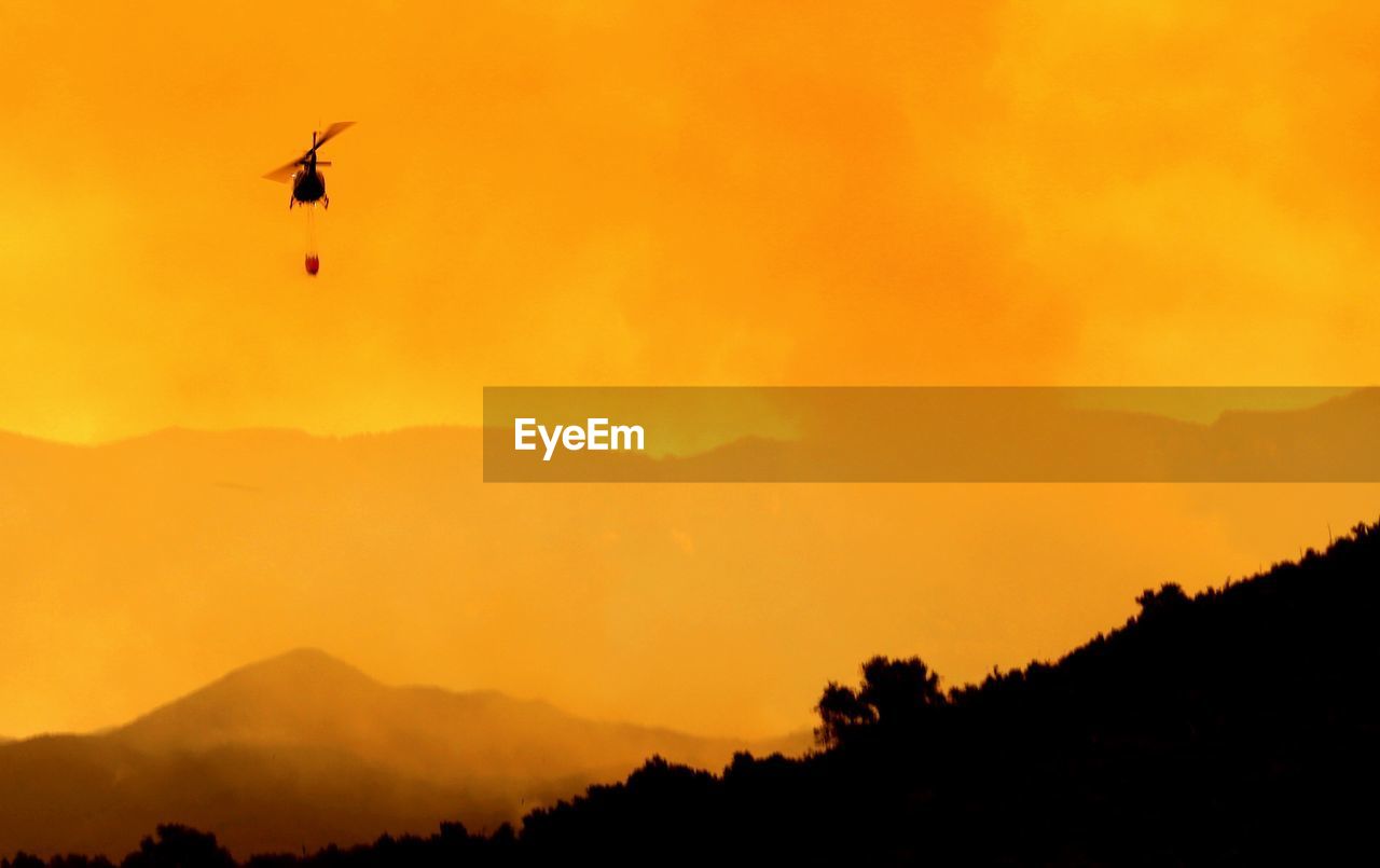 Helicopter against mountains during wildfire