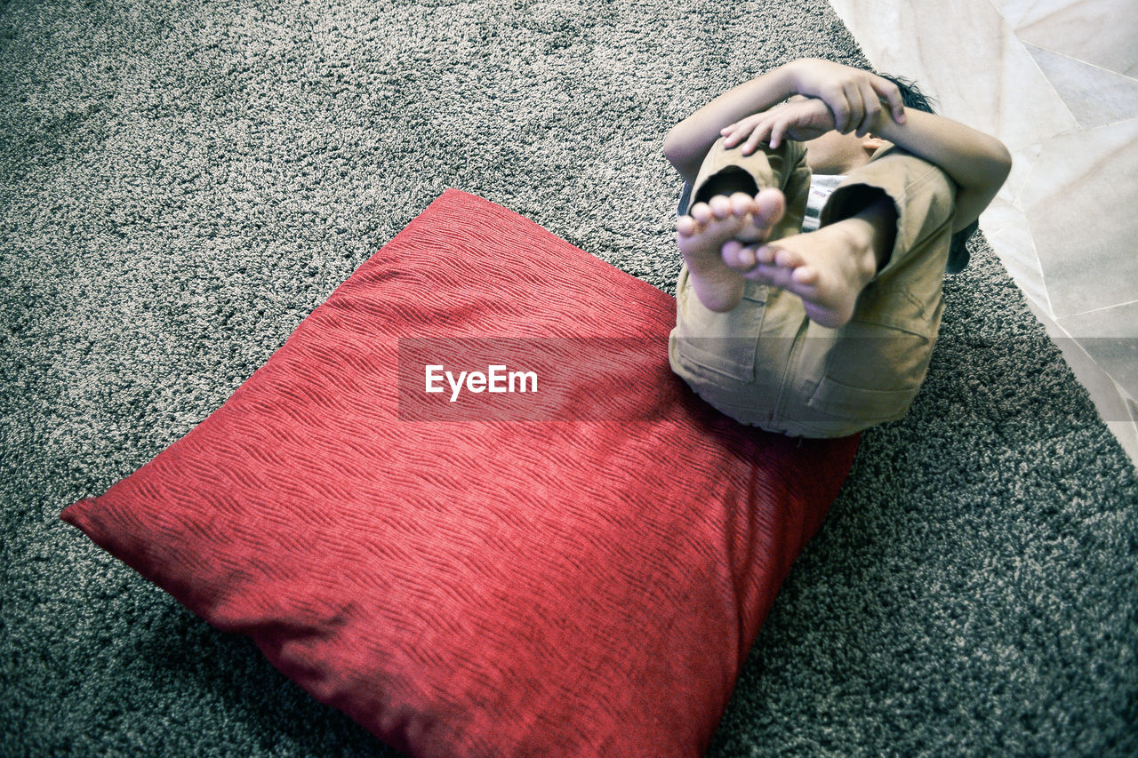 High angle view of boy relaxing on rug at home