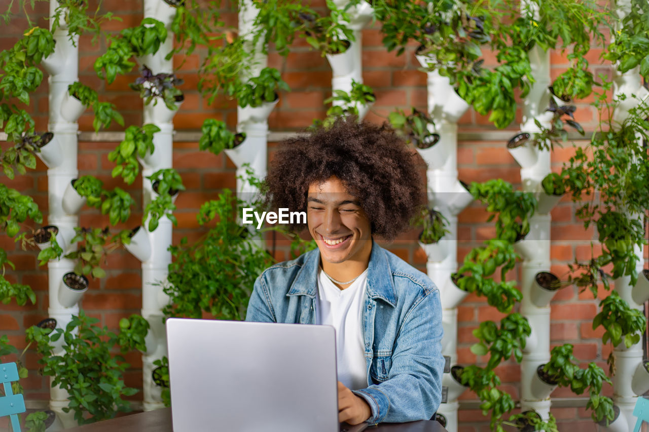 portrait of smiling young woman using digital tablet while standing against trees