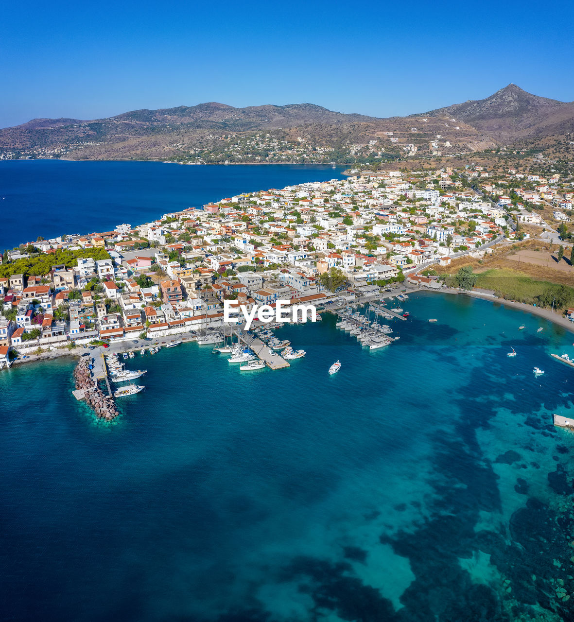 HIGH ANGLE VIEW OF CITY BY SEA AGAINST BLUE SKY