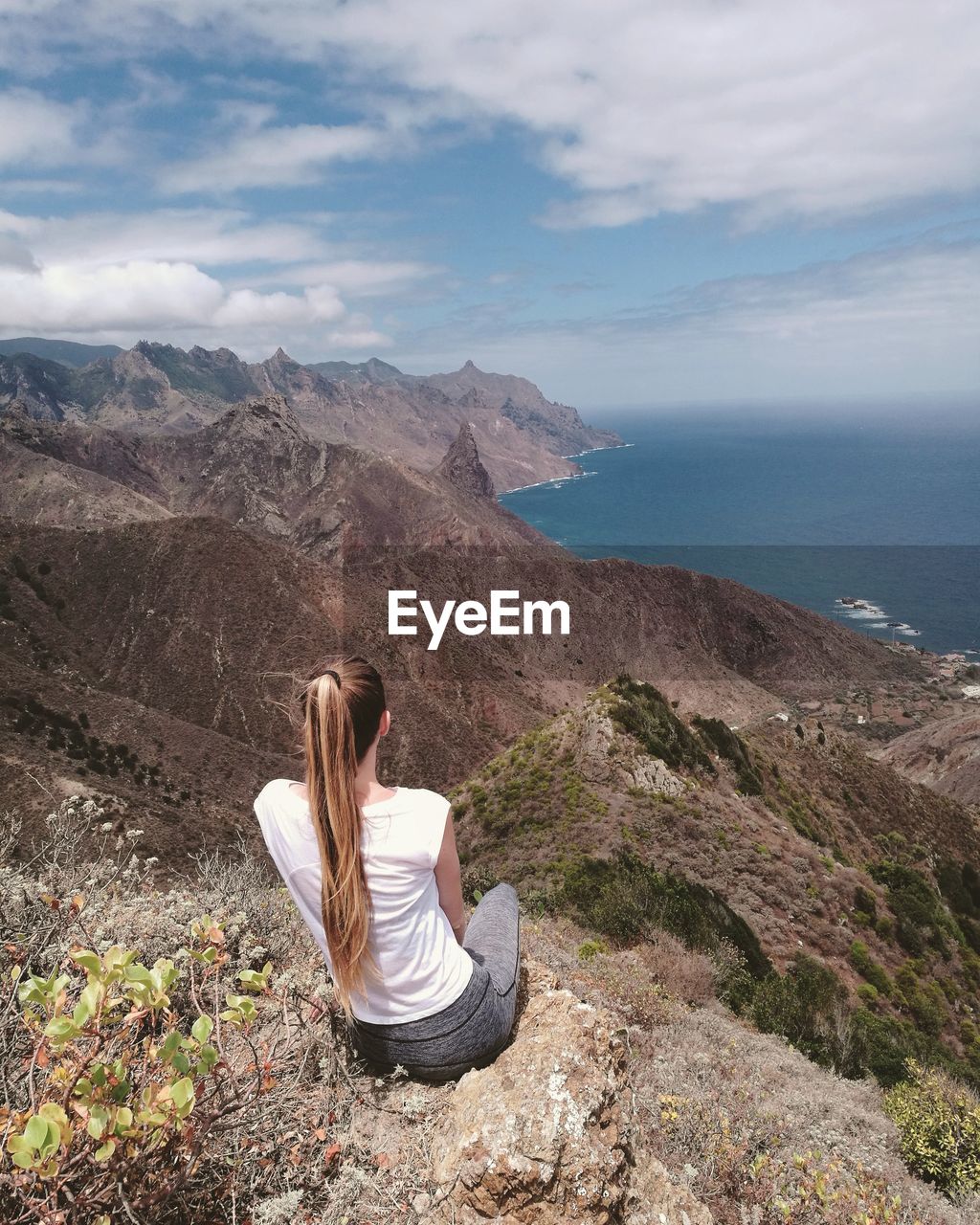 Rear view of woman on mountain looking at sea