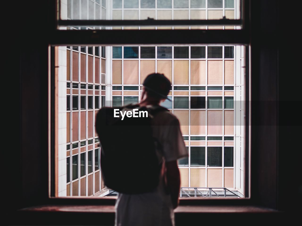 Rear view of man looking through window at customs house