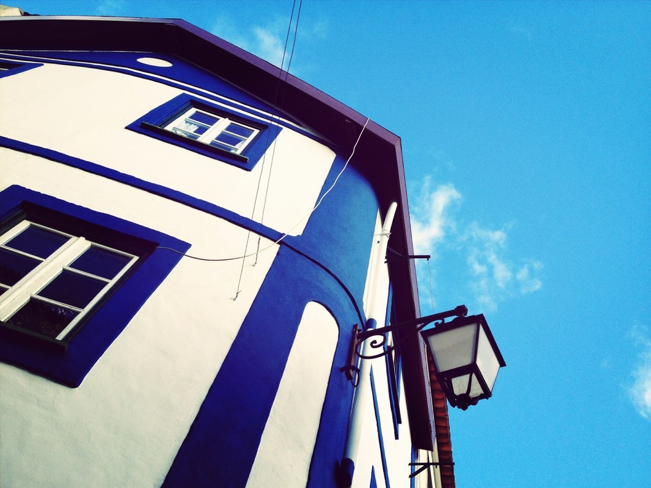 Low angle view of retro-styled lamp on building wall against sky at monchique