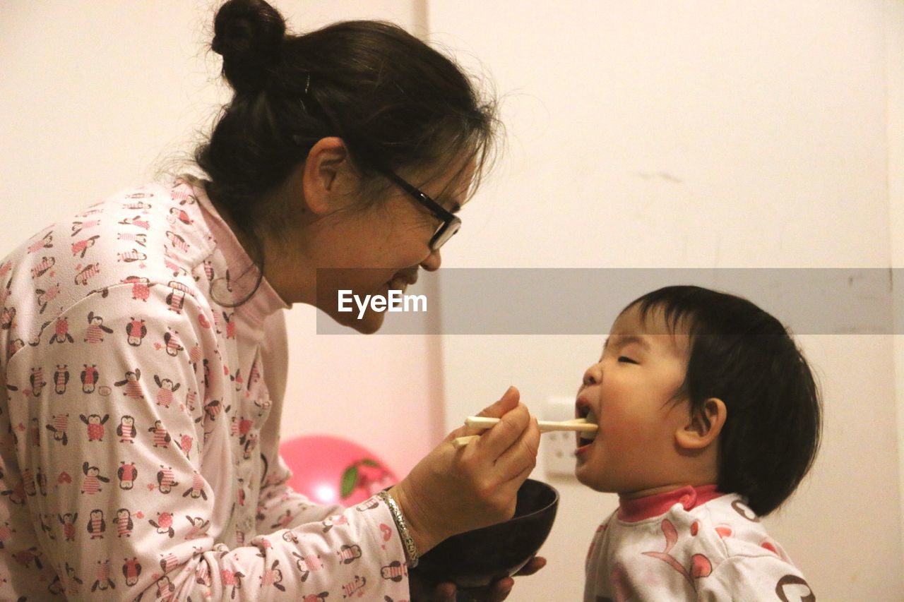 Mother feeding son with asian food