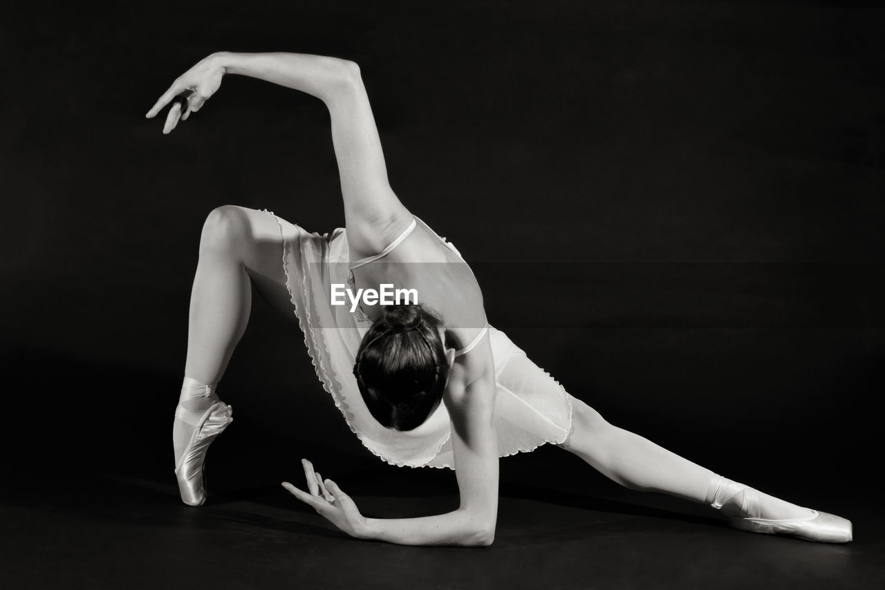 Young woman dancing against black background