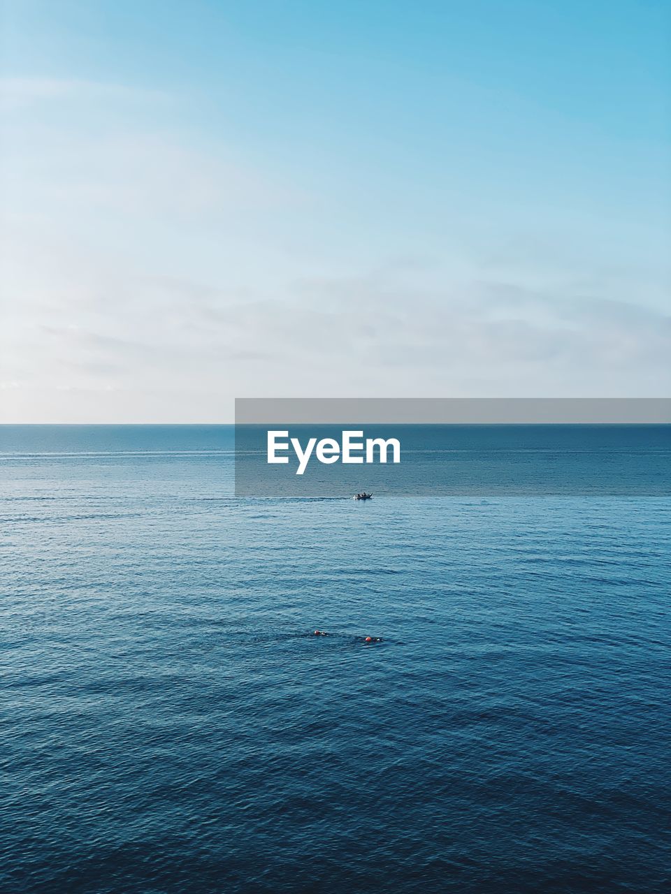 Scenic view of sea against sky with horizon over the sea at dawn and a tiny boat 
