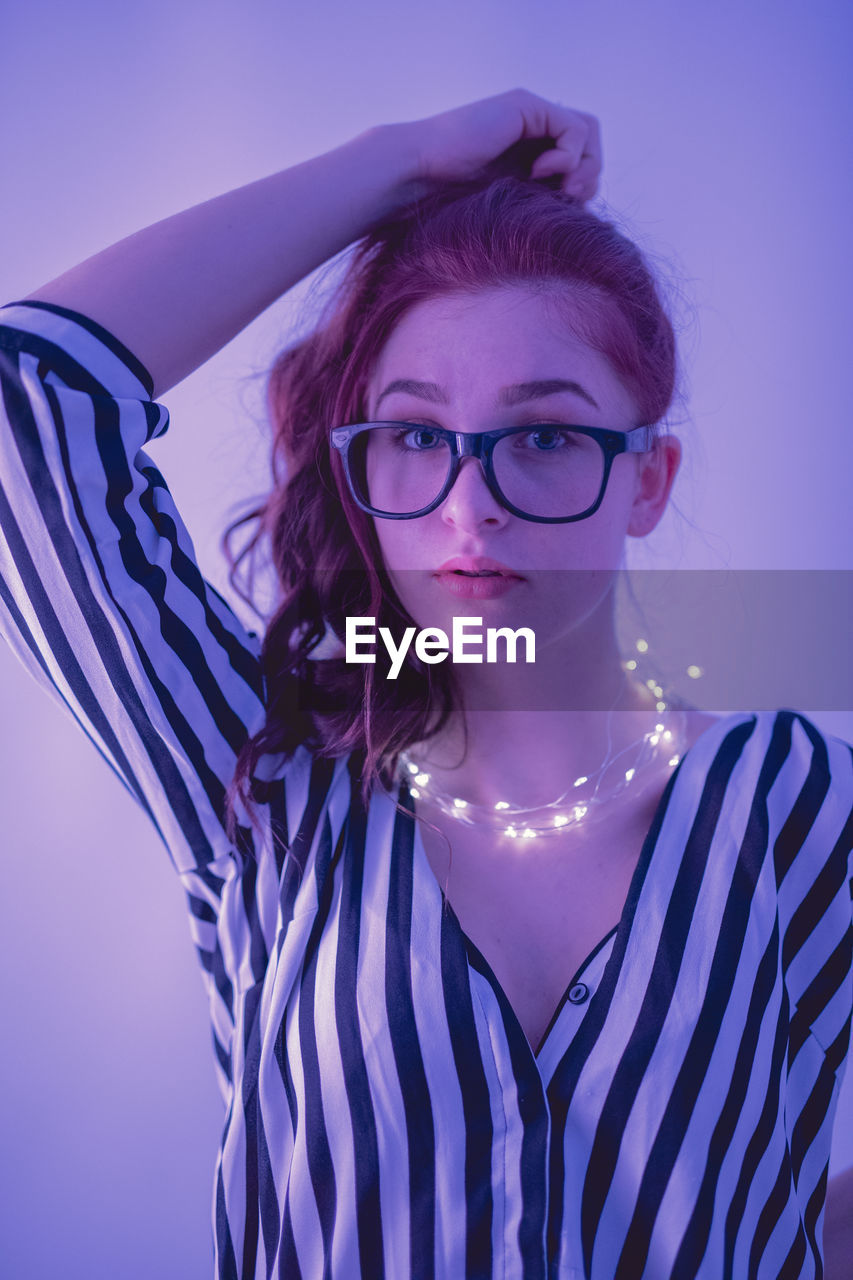 Young woman with illuminated string light against blue background