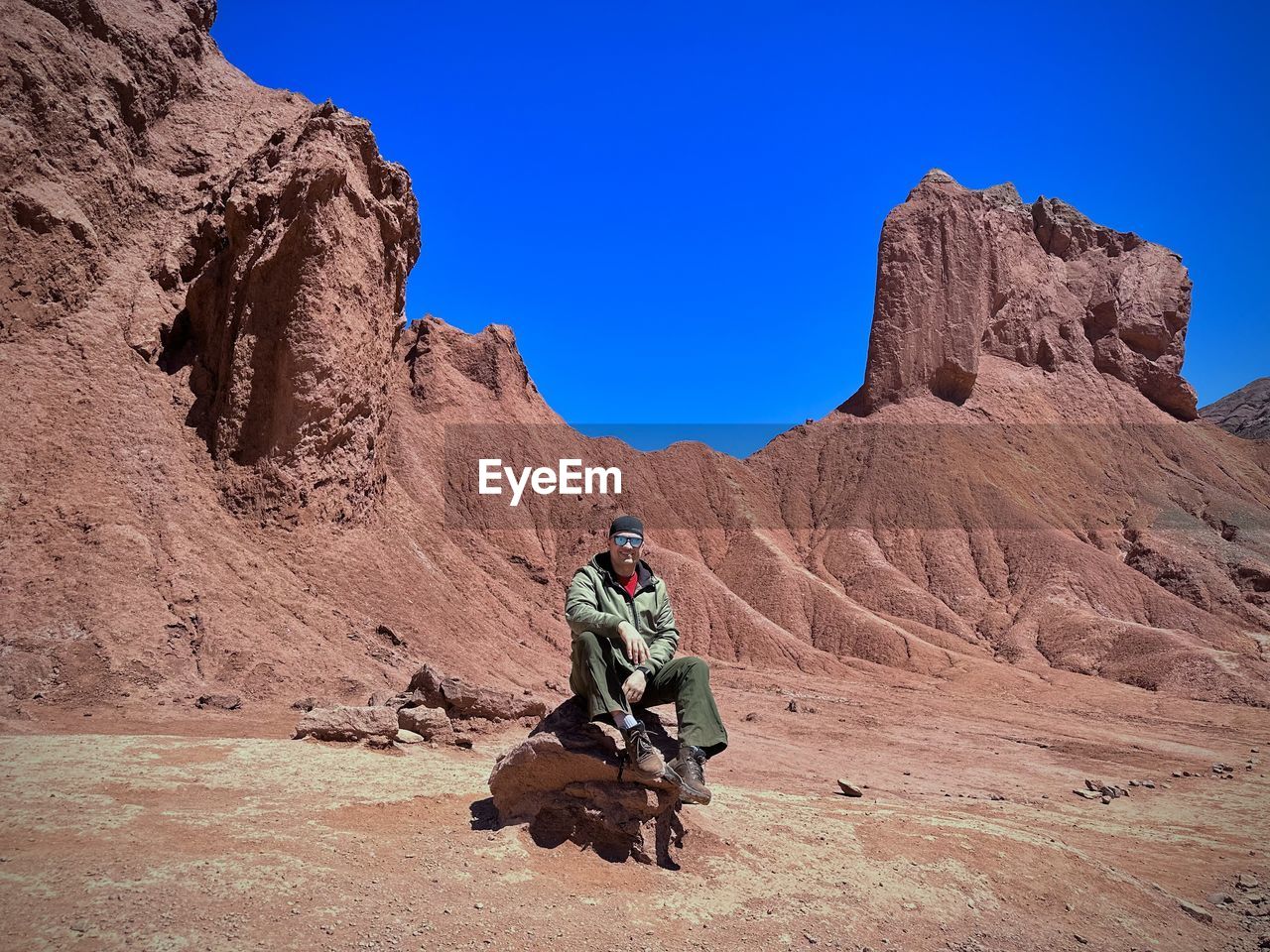 rock, desert, nature, landscape, scenics - nature, valley, environment, travel, wadi, natural environment, travel destinations, rock formation, sky, mountain, one person, land, wilderness, geology, activity, beauty in nature, full length, climate, adventure, adult, terrain, clear sky, hiking, leisure activity, arid climate, blue, outdoors, plateau, day, non-urban scene, sunny, extreme terrain, backpack, tourism, mountain range, sunlight, men, remote, canyon, sports, tranquility