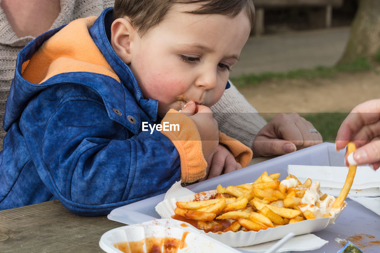 Boy with parent having french fries at table