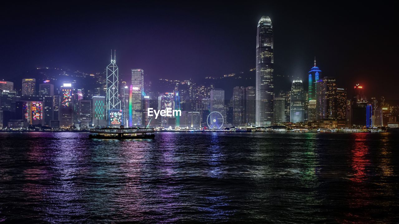 Victoria harbour against illuminated city at night