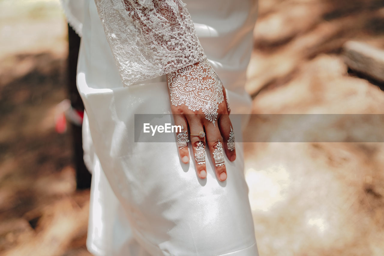 Midsection of bride wearing wedding dress while standing outdoors